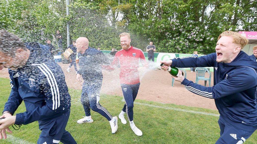 Hiermit fing die rauschende Feier von Kickers Emden an: Unmittelbar nach dem Abpfiff in Egestorf griff Pascal Steinwender zur Sektflasche und machte das Trainerteam (links Co-Trainer Markus Unger) nass. Foto: Doden, Emden