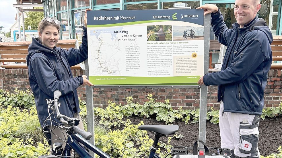 Paulina Richter und Björn Schumacher von der NBG präsentieren die neu gelayoutete Infotafel zum Emsradweg vor der Tourist-Information. Foto: NBG