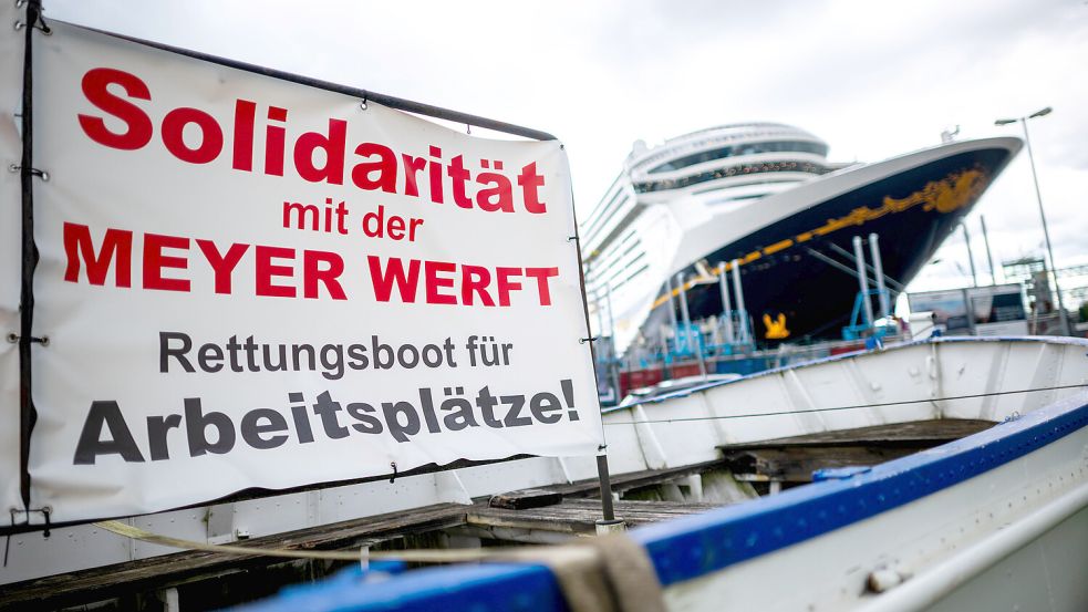 11. September in Papenburg, als der Einstieg des Staates beschlossen und verkündet wurde: Das Kreuzfahrtschiff „Disney Treasure“ liegt vor der Meyer Werft an der Ems – mit einer eindeutigen Botschaft aus dem Rettungsboot. Foto: Schuldt/DPA